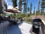 Deck furnished with table, chairs, umbrellas, lounger, and gas grill 
